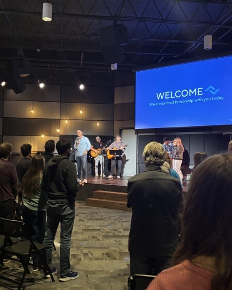 Worship band leading the gathering with the WELCOME screen behind